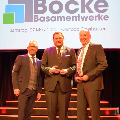 Jubiläum: 100 Jahre Basamentwerke Böcke GmbH

Duisburg, 6. April 2020

Am 7. März 2020 feierte die Basamentwerke Böcke GmbH ihr 100-jähriges Firmenjubiläum im Oberhausener Ebertbad. Zu den Gästen gehörten, neben allen Mitarbeiter/innen und Ehemaligen, auch Daniel Schranz, Oberbürgermeister der Stadt Oberhausen, sowie Raimo Benger, vero-Hauptgeschäftsführer.

Der Gastgeber des Abends, Dr. Thomas Böcke, hielt die Festrede zum Jubiläum. Die imposante Bilderzeitreise durch die letzten 100 Jahre des Basamentwerkes Böcke wurde ergänzt durch ein unterhaltsames Rahmenprogramm mit Zauberern, Musik und Comedy.

Auch vero-Hauptgeschäftsführer Raimo Benger gratulierte dem Mitgliedsunternehmen. „Glückwünsche an ein innovatives Unternehmen, das seit hundert 100 Jahren sichere Arbeits- und Ausbildungsplätze in der Region sichert“, so Benger in seiner Laudatio.

Von seinen Mitarbeitern und Mitarbeiterinnen erhielt der Thomas Böcke ein Präsent in Form einer Betonplatte mit dem aktuellen Firmenlogo und Gravur. Ein gemeinsames Gruppenbild mit allen aktiven Mitarbeitern und Mitarbeiterinnen war der Höhepunkt des Abends. „Gemeinsamkeit und Zusammenhalt ist uns wichtig. Dieses Bild steht symbolisch dafür. Es ziert unsere Danksagungskarten und wird künftig auch in allen Standorten an den Wänden hängen“, so Thomas Böcke.

Web Pressefoto Gruppenfoto Basamentwerke Boecke

Starker Zusammenhalt: Gruppenbild aller aktiven Mitarbeiter/innen der Basamentwerke Böcke GmbH

Web Pressefoto Jubilaeum Basamentwerke Boecke

(v.l.n.r.) Oliver Nuth, Geschäftsführer Böcke, Daniel Schranz, Oberbürgermeister der Stadt Oberhausen, Dr. Thomas Böcke, Geschäftsführer Böcke